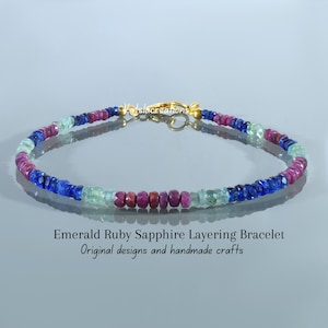 Peut inclure: Un bracelet de perles composé de pierres précieuses facettées émeraude, rubis et saphir dans des tons vert, rouge et bleu. Le bracelet comprend un fermoir en métal doré et porte le texte Emerald Ruby Sapphire Layering Bracelet.