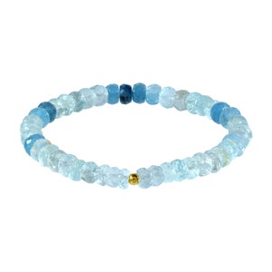 May include: A light blue aquamarine gemstone bracelet with a gold bead accent. The bracelet is made of small, faceted beads that are graduated in size, creating a gradient effect.