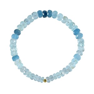 May include: A light blue aquamarine gemstone bracelet with a gold bead accent. The bracelet is made of faceted beads and is strung on a stretchy cord.