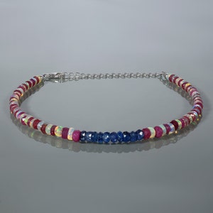 Puede incluir: Un collar de cadena de plata con un diseño de cuentas de piedras preciosas multicolores. El collar presenta cuentas alternas de ópalo blanco, rubí rosa y zafiro azul.