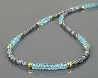 May include: A necklace made of light blue faceted beads and gray beads with gold accents.