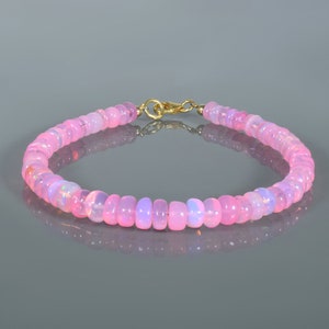 Peut inclure: Un bracelet en perles d'opale rose avec un fermoir en or. Le bracelet est composé de petites perles rondes enfilées sur une fine chaîne en or.