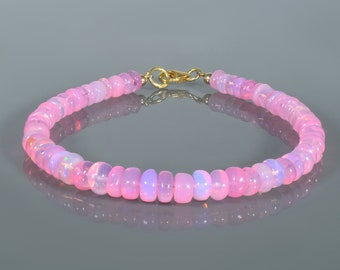 May include: A pink opal beaded bracelet with a gold clasp. The bracelet is made of small, round beads that are strung together on a thin gold chain.