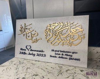 May include: A white canvas with gold Arabic calligraphy and a black heart with the text "Riz & Ammamh 28th July 2023". The text "He put between you Love & Mercy Surah Ar-Rum (30:21)" is written in black below the calligraphy.