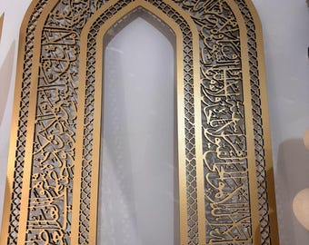 Può includere: Un arco in legno color oro con intricati tagli e calligrafia araba. L'arco è fatto di un unico pezzo di legno e ha un design islamico tradizionale.