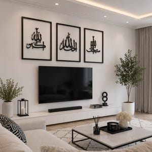 May include: A modern living room with a white sofa, a marble coffee table, and a large flat-screen TV. Three framed black and white Islamic calligraphy art pieces hang above the TV. Decorative plants and a black candle lantern add to the room's aesthetic.