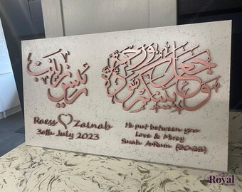 May include: A white canvas with a rose gold Arabic calligraphy design. The names "Roess" and "Zainab" are written below the calligraphy, along with the date "30th July 2023". The text "He put between you Love & Mercy Surah Ar-Rum (30:21)" is written below the names.