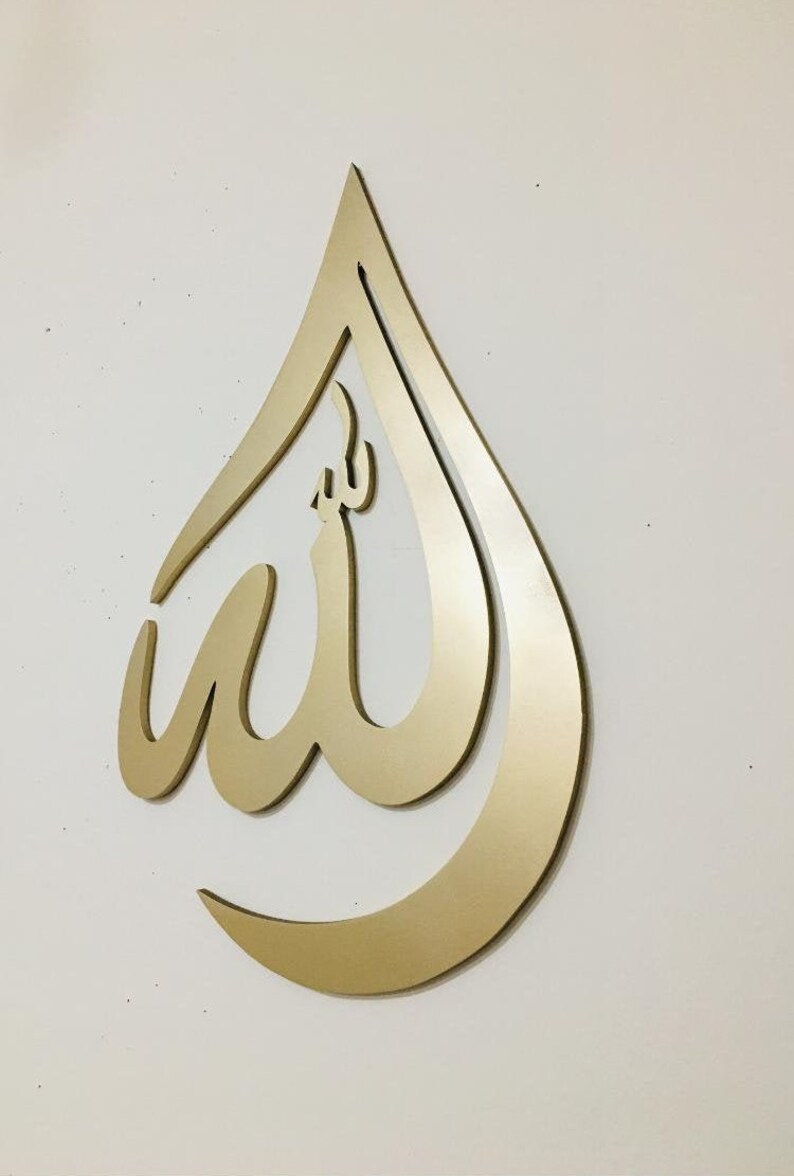May include: Gold-colored metal wall decor in the shape of a teardrop with the Arabic word "Allah" inscribed inside.