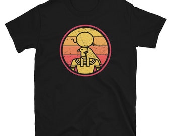 May include: Black t-shirt featuring a retro-style graphic of an Egyptian god with a sun behind him. The graphic is in shades of yellow, orange, red, and pink.