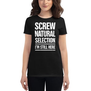 Puede incluir: Camiseta negra para mujer con texto blanco que dice "SCREW NATURAL SELECTION I'M STILL HERE".