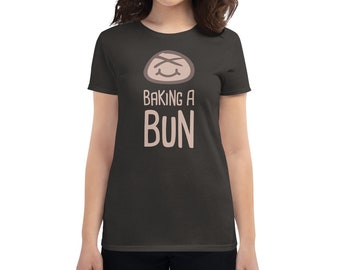 May include: A dark gray women's t-shirt with a cartoon bun with a smiling face and the text "Baking a Bun" in white.