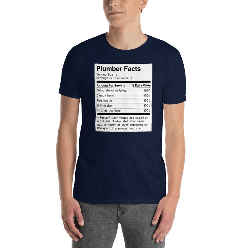 May include: A navy blue t-shirt featuring a white graphic of a nutrition facts label for "Plumber Facts". The label lists the daily value of "Fixing stupid mistakes", "Steady hand", "Pipe master", "Multi-tasker", and "Strange positions", all at 100%.