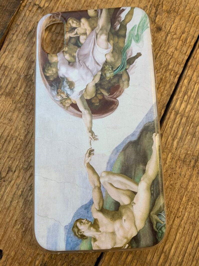 Puede incluir: Una funda transparente para tel&eacute;fono con una imagen impresa de La Creaci&oacute;n de Ad&aacute;n de Miguel &Aacute;ngel. La imagen muestra a Dios tendi&eacute;ndole la mano a Ad&aacute;n, que est&aacute; acostado sobre una roca.