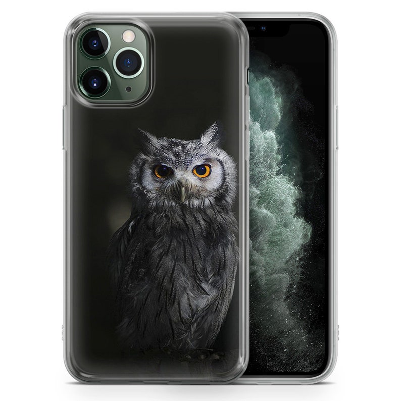 May include: A clear phone case with a black and white image of an owl with yellow eyes. The owl is facing forward and has its wings folded. The phone case is designed for an iPhone.