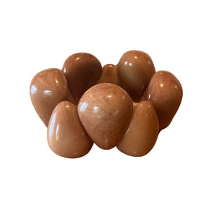 May include: A brown, smooth, rounded, decorative bowl made of stone. The bowl is shaped like a flower with multiple petals.
