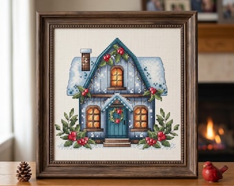 May include: Cross-stitch artwork of a winter house scene in a wooden frame. The house is blue with a snow-covered roof, adorned with red berries and a green wreath on the door. The artwork is displayed on a wooden surface.