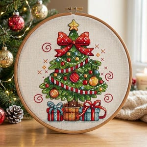 May include: A cross-stitch embroidery of a Christmas tree in a wooden hoop. The tree is decorated with ornaments, a red bow, and a star. Two wrapped gifts sit at the base of the tree. The embroidery is on a beige fabric.