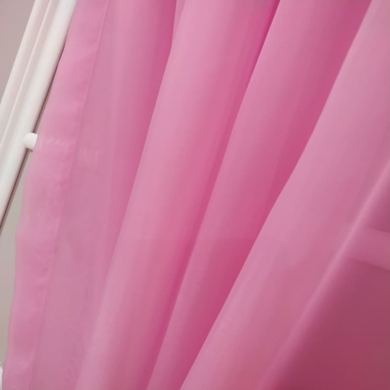 May include: Close-up of a pink sheer curtain with soft folds and a smooth texture.