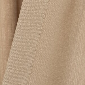 May include: Close-up of a beige fabric with a subtle texture and a straight seam running down the center.
