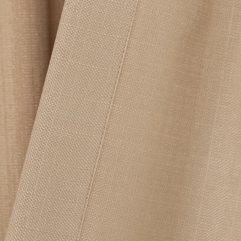 May include: Close-up of a beige fabric with a subtle texture and a straight seam running down the center.