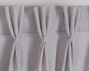 May include: A close-up of a set of gray curtains with pleats. The curtains are made of a textured fabric.