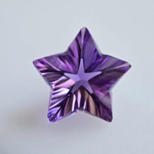 May include: A purple star-shaped amethyst gemstone with a faceted cut.