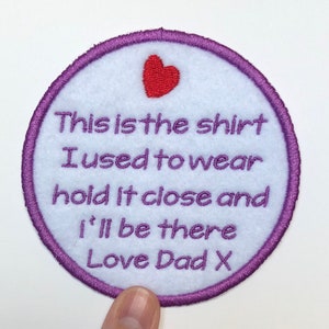 May include: A white, round, felt patch with a purple border. The patch has a red heart and the text "This is the shirt I used to wear hold it close and I'll be there Love Dad X".