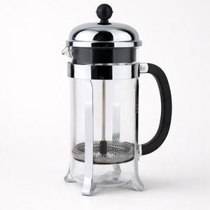 Può includere: Una caffettiera a pistone in vetro trasparente con telaio e coperchio in acciaio inossidabile. Ha un manico nero e un meccanismo a stantuffo all'interno. La caffettiera è progettata per preparare il caffè.