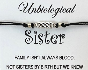 May include: A black string bracelet with a silver infinity symbol charm and the word "Sister" written in a decorative font. The card reads "Unbiological Sister. Family isn't always blood, not sisters by birth but we knew from the start, we always would be sisters by heart. Thank you for being my unbiological sister!"