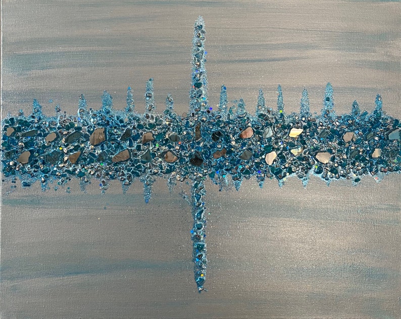 May include: Abstract artwork on canvas featuring a horizontal band of blue and silver stones and glitter. A vertical line of the same materials intersects the horizontal band. The background is a light blue and silver gradient.