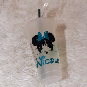 Puede incluir: Un vaso de pl&aacute;stico transparente con una pajita verde azulado. El vaso presenta una silueta negra de Minnie Mouse con un lazo verde azulado y el nombre "Nicole" en letras brillantes verde azulado. La taza tiene un logotipo de Starbucks.