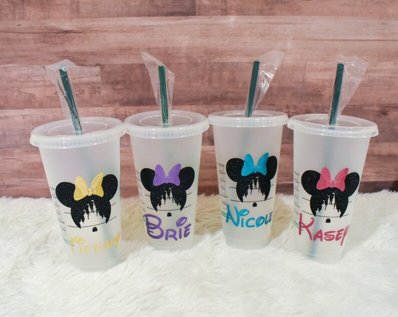 Puede incluir: Cuatro vasos fr&iacute;os de pl&aacute;stico transparente con tapas y pajitas. Cada vaso presenta una silueta negra de Minnie Mouse con un lazo colorido y un nombre en un color coordinado: Tiffany, Brie, Nicole y Kasey. Los vasos est&aacute;n sobre una superficie blanca.
