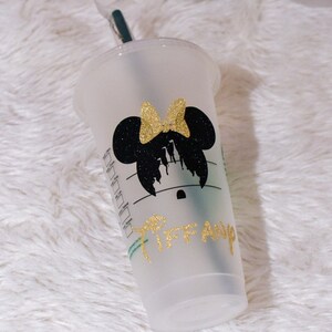 Puede incluir: Un vaso de pl&aacute;stico transparente con un dise&ntilde;o de silueta de Minnie Mouse negra y un lazo dorado con purpurina. El nombre "Tiffany" est&aacute; escrito en letras doradas con purpurina. Incluye una pajita verde y una tapa transparente.