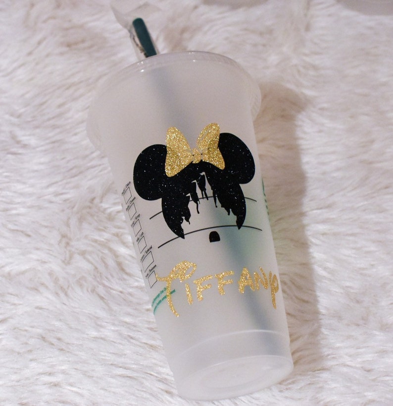 Puede incluir: Un vaso de pl&aacute;stico transparente con un dise&ntilde;o de silueta de Minnie Mouse negra y un lazo dorado con purpurina. El nombre "Tiffany" est&aacute; escrito en letras doradas con purpurina. Incluye una pajita verde y una tapa transparente.