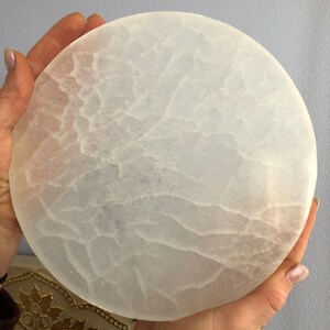 May include: A white selenite charging plate with a circular shape and a textured surface.