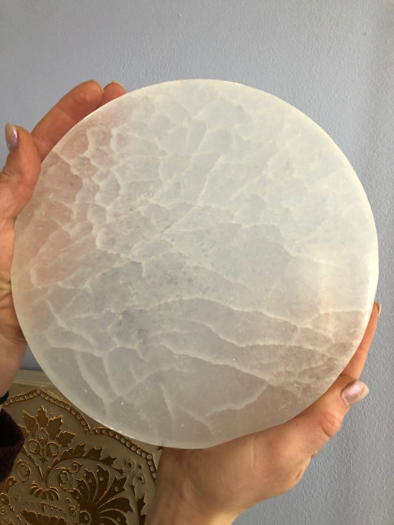 May include: A white selenite charging plate with a circular shape and a textured surface.