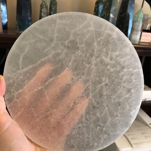 May include: A large, round, clear selenite charging plate with a textured surface. The plate is approximately 8 inches in diameter.