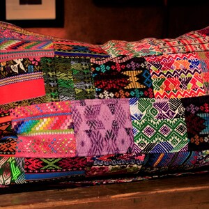 May include: A colorful patchwork pillow with a variety of geometric patterns in shades of red, green, blue, purple, and pink.