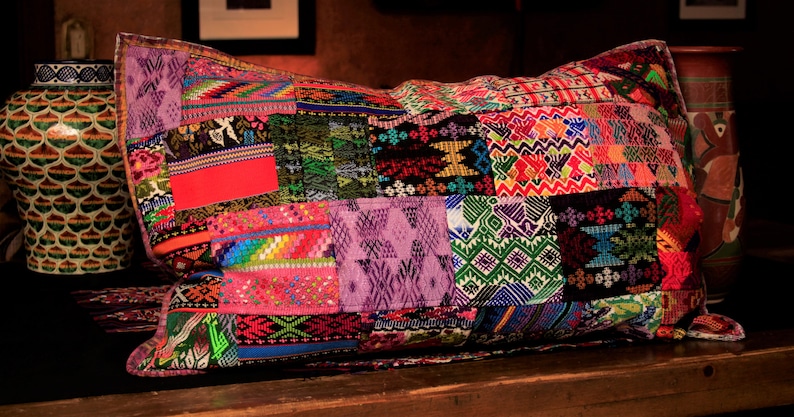 May include: A colorful patchwork pillow with a variety of geometric patterns in shades of red, green, blue, purple, and pink.