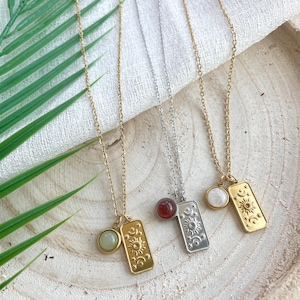 Könnte beinhalten: Drei goldene Halsketten mit einem Sonnen- und Mond-Anhänger und einem kleinen Edelstein-Anhänger. Die Edelsteine sind grün, rot und weiß.