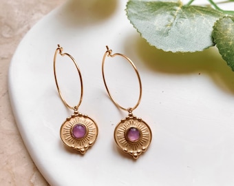 May include: Gold hoop earrings with a small purple gemstone in a sunburst design pendant.