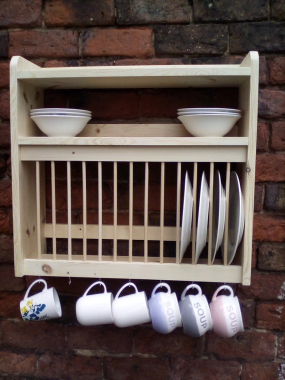 Dish Rack Holds Many Dishes And Cups Against Wooden Countertop