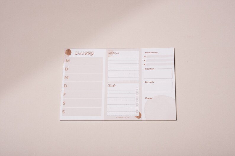 May include: A weekly planner with sections for "Wochensziele" (weekly goals), "Intention", "For mich" (for me), "To do", and "Focus". The planner has a light brown background with a brown watercolor design.