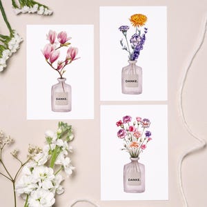 Può includere: Tre stampe artistiche floreali con illustrazioni ad acquerello di fiori in vasi di vetro. Ogni vaso ha un'etichetta con la parola "DANKE". I fiori includono magnolie rosa, fiori gialli e viola e un bouquet di colori misti.