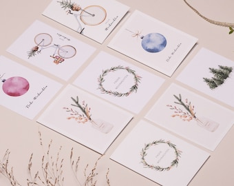May include: A collection of watercolor Christmas cards featuring festive designs. The cards showcase illustrations of ornaments, wreaths, bicycles with holiday decor, and floral arrangements. Each card has the phrase "Frohe Weihnachten" in a script font.