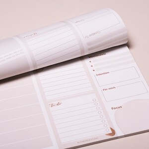 May include: A weekly planner with a beige background and brown text. The planner has sections for daily tasks, to-do lists, weekly goals, intentions, and a focus area. The planner also has a section for "For me".