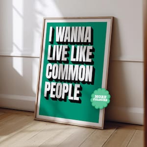 May include: A teal green poster with white text that reads "I wanna live like common people". The poster has a small green circle with white text that reads "More Colours" in the bottom right corner.