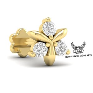 Può includere: Un anello per il naso in oro con tre diamanti rotondi incastonati in un design floreale. L'anello per il naso è attaccato a un piccolo perno in oro.