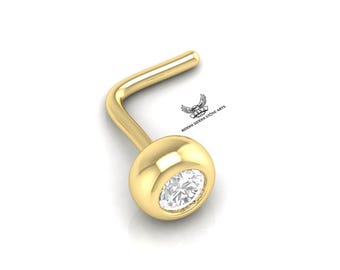 May include: A gold nose ring with a clear round gemstone.