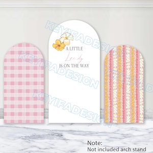 May include: Three arched display panels. The left panel features a pink and white plaid pattern. The centre white panel displays yellow floral illustrations and the text A LITTLE Leidy IS ON THE WAY. The right panel has vertical floral stripes.